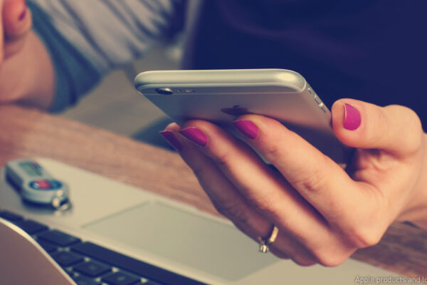 Person sitting at laptop computer holding smartphone