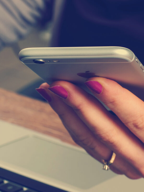 Person sitting at laptop computer holding smartphone