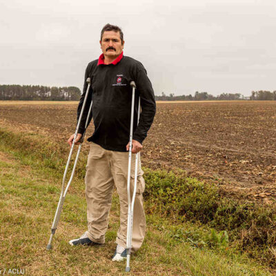 Arturo Hernandez stands on crutches in a field in North Carolina.