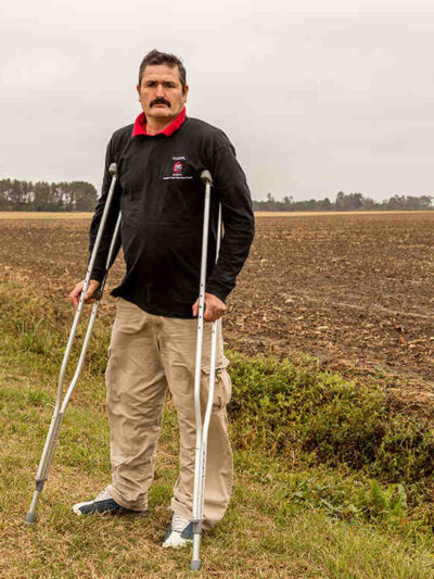 Arturo Hernandez stands on crutches in a field in North Carolina.