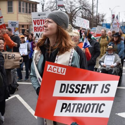 Protester holds an ACLU sign that says "Dissent is Patriotic"