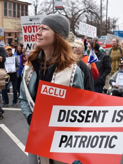 Protester holds an ACLU sign that says "Dissent is Patriotic"