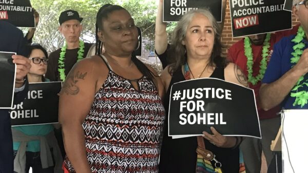 The mother of Soheil Antonio Mojarrad holds a "Justice for Soheil" sign at a PACT rally