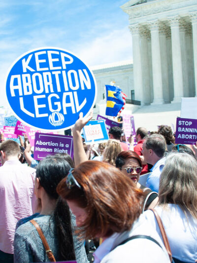 A crowd of pro-choice protesters standing outside the Supreme Court holding up signs that read "Keep Abortion Legal," and "Abortion is a Human Right" among other signs.