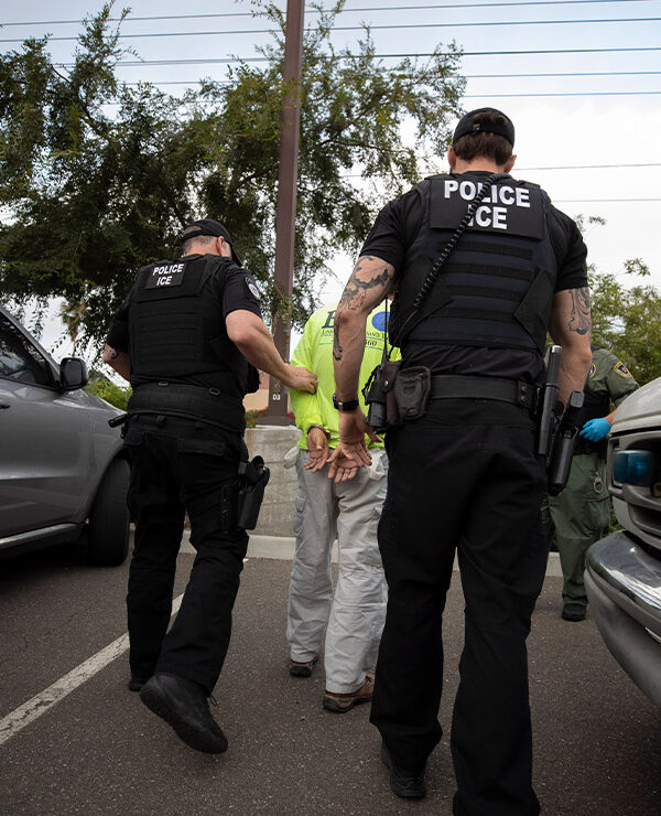 On a sunny day in California, two Immigration and Customs Enforcement (ICE) officers escort a man in handcuffs. Trump administration officials have confirmed plans for two new tactics in their anti-immigrant agenda.