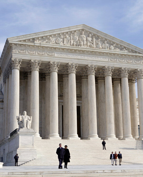 The front of the Supreme Court, as a few people are walking up and down its stairs, on a sunny day in 2012.