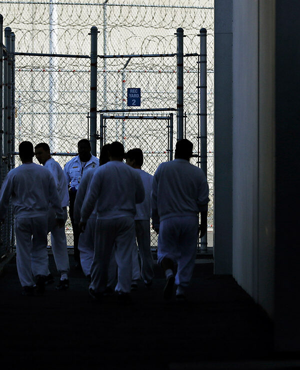Detainees walk toward a fenced recreation area inside of an ICE detention facility in Washington state.