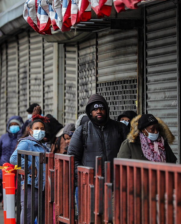 Customers in masks line up outside a grocery store in Brooklyn, NY, waiting to enter after other shoppers have left, because of social distancing efforts during the coronavirus outbreak.