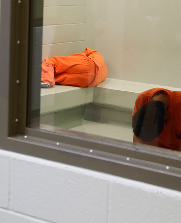Three detainees waiting together inside a room to be processed at a detention facility.