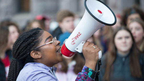 A Black woman speaks into a bullhorn