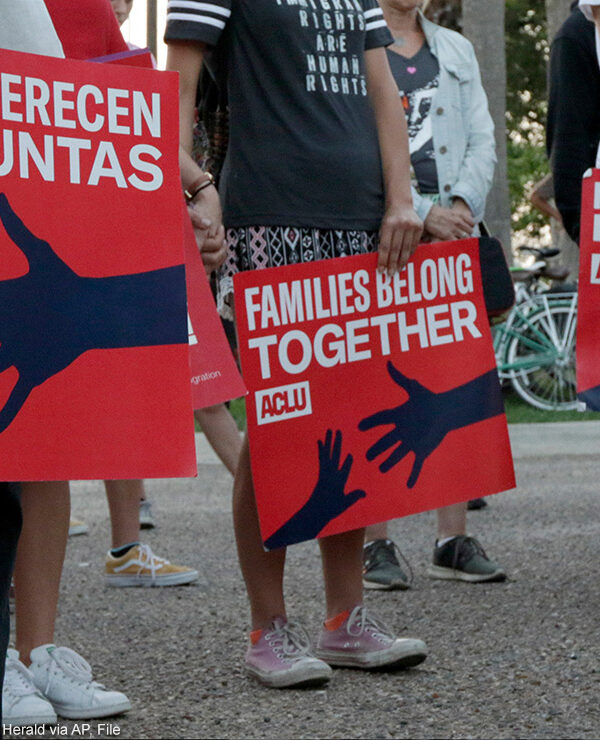 People hold signs that read "families belong together" in both English and Spanish during a vigil.