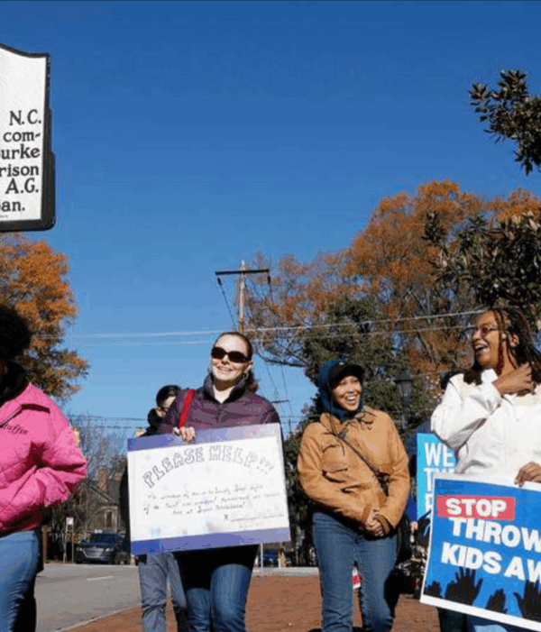 A group of protesters walk past the Governor's Mansion historical marker.