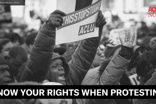 An image of a protest. In the foreground, a Black man holds a sign that says "This Stops Today" with the ACLU logo. The graphic says "Know your rights when protesting" and has the ACLU of NC and an image credit.