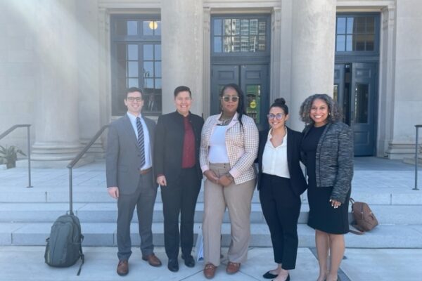 Five people stand in front of the Mecklenburg County Courthouse in Charlotte, NC. Names listed in caption.