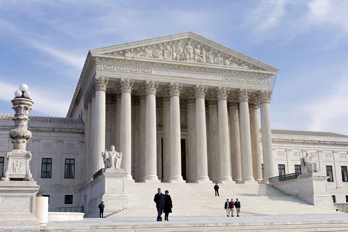 The front of the Supreme Court, as a few people are walking up and down its stairs, on a sunny day in 2012.