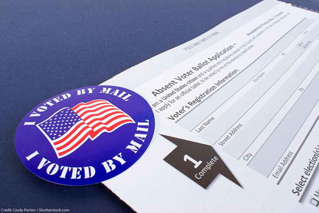 An absentee voter ballot next to a blue "I voted by mail" sticker.