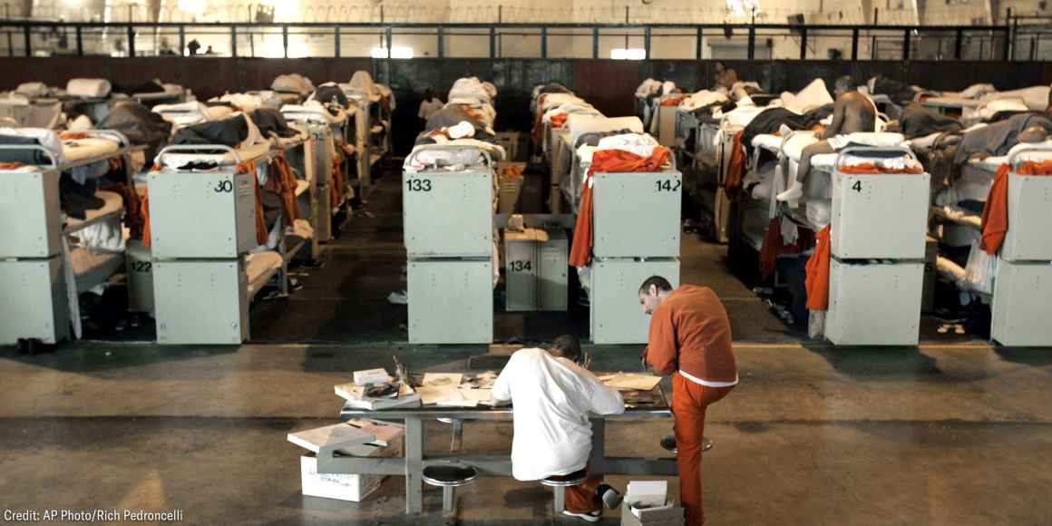 Incarcerated people lying in rows of prison bunk beds.