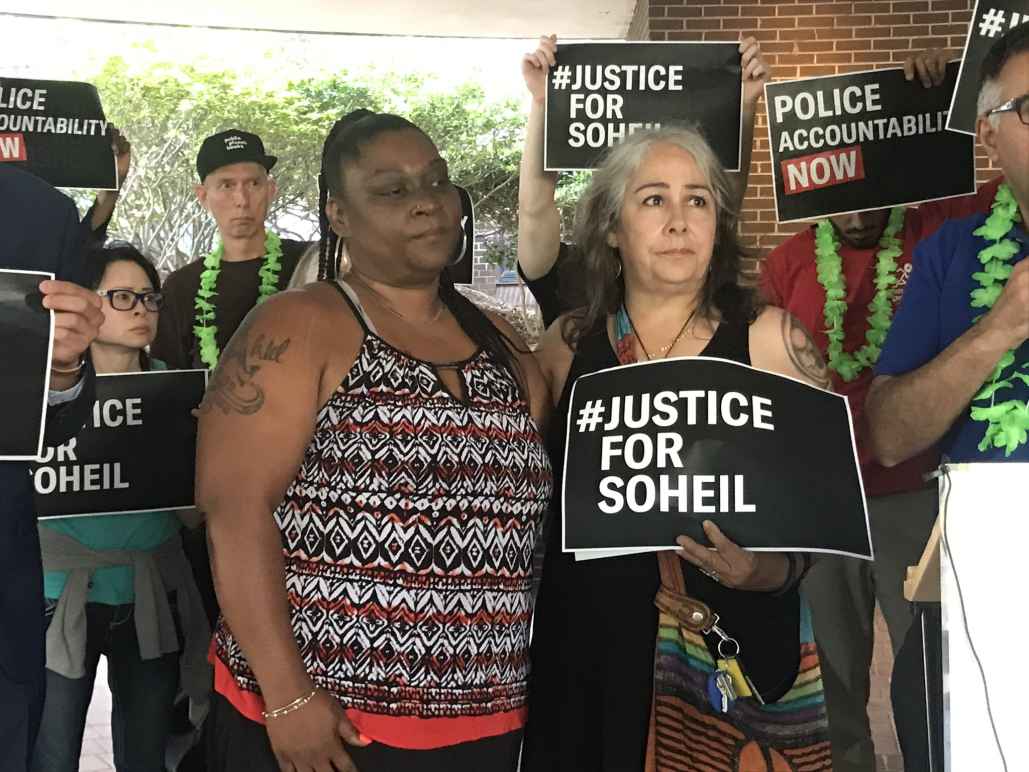 The mother of Soheil Antonio Mojarrad holds a "Justice for Soheil" sign at a PACT rally