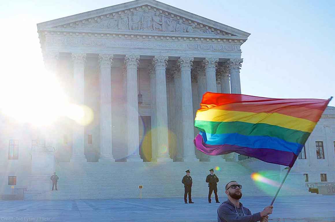 Man waving rainbow flag in front of Supreme Court
