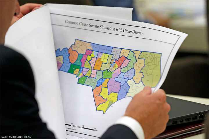 An elected official reviews a map of North Carolina districts at select committee meeting on redistricting.