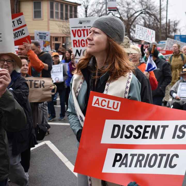 Protester holds an ACLU sign that says "Dissent is Patriotic"