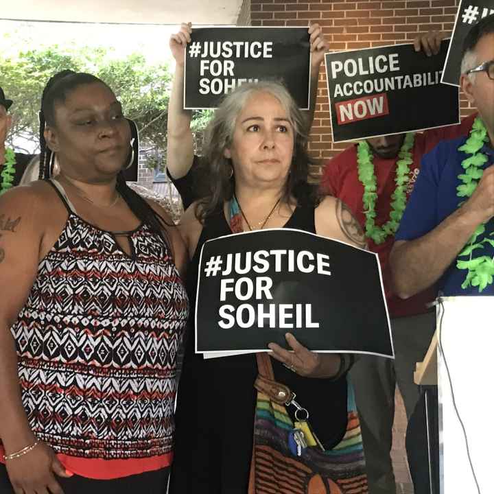 The mother of Soheil Antonio Mojarrad holds a "Justice for Soheil" sign at a PACT rally